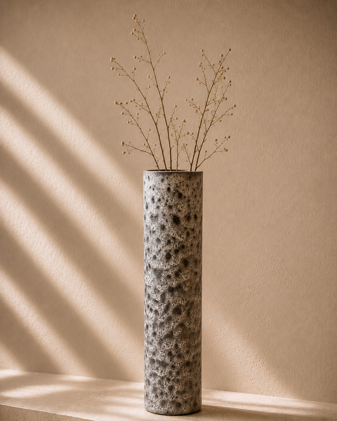 Volcanic Speckle Column Vase styled with dried stems on a warm stone surface